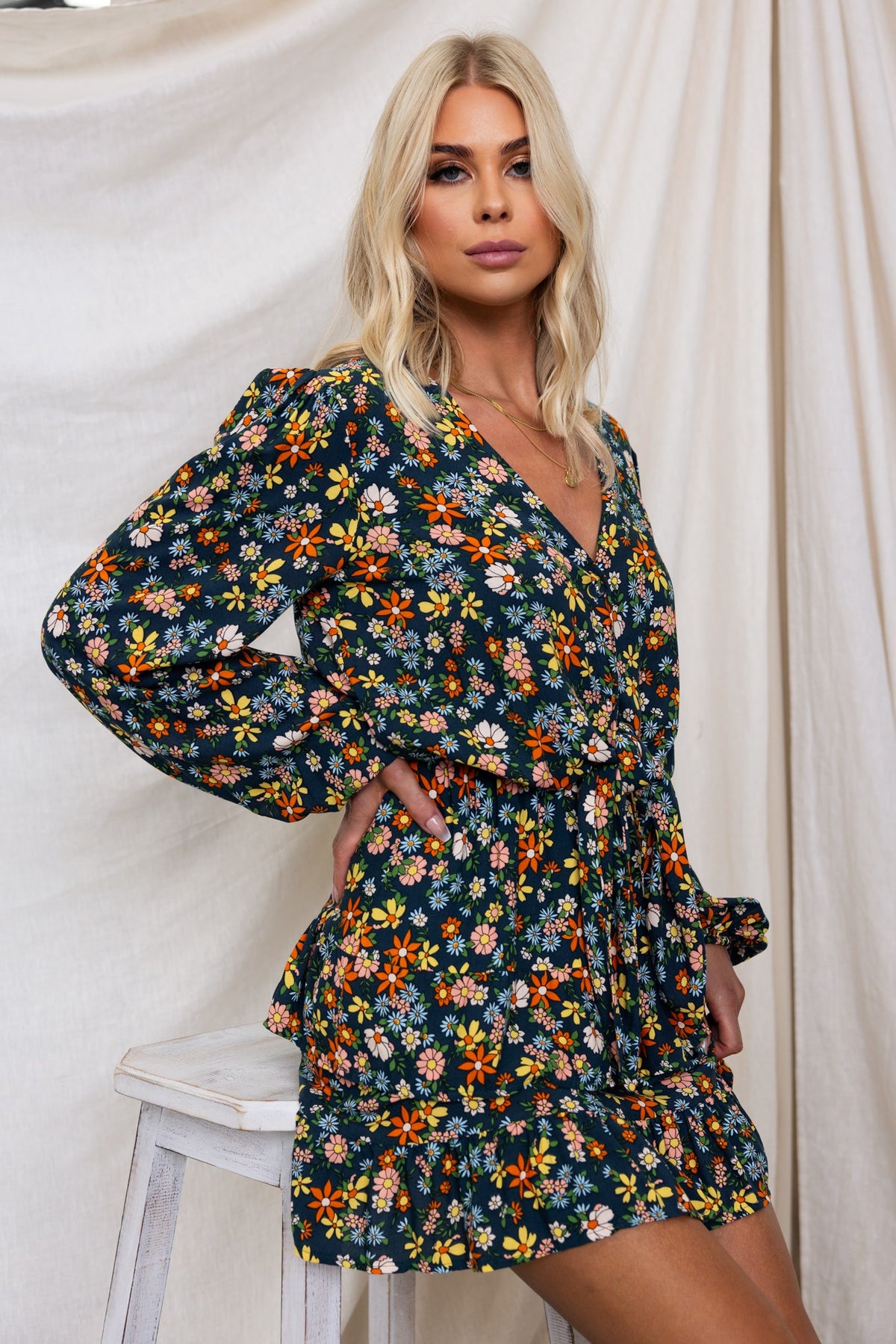 Model wearing a floral navy Lanter Dress with V-neckline, elastic sleeves, and a tie at the bust.