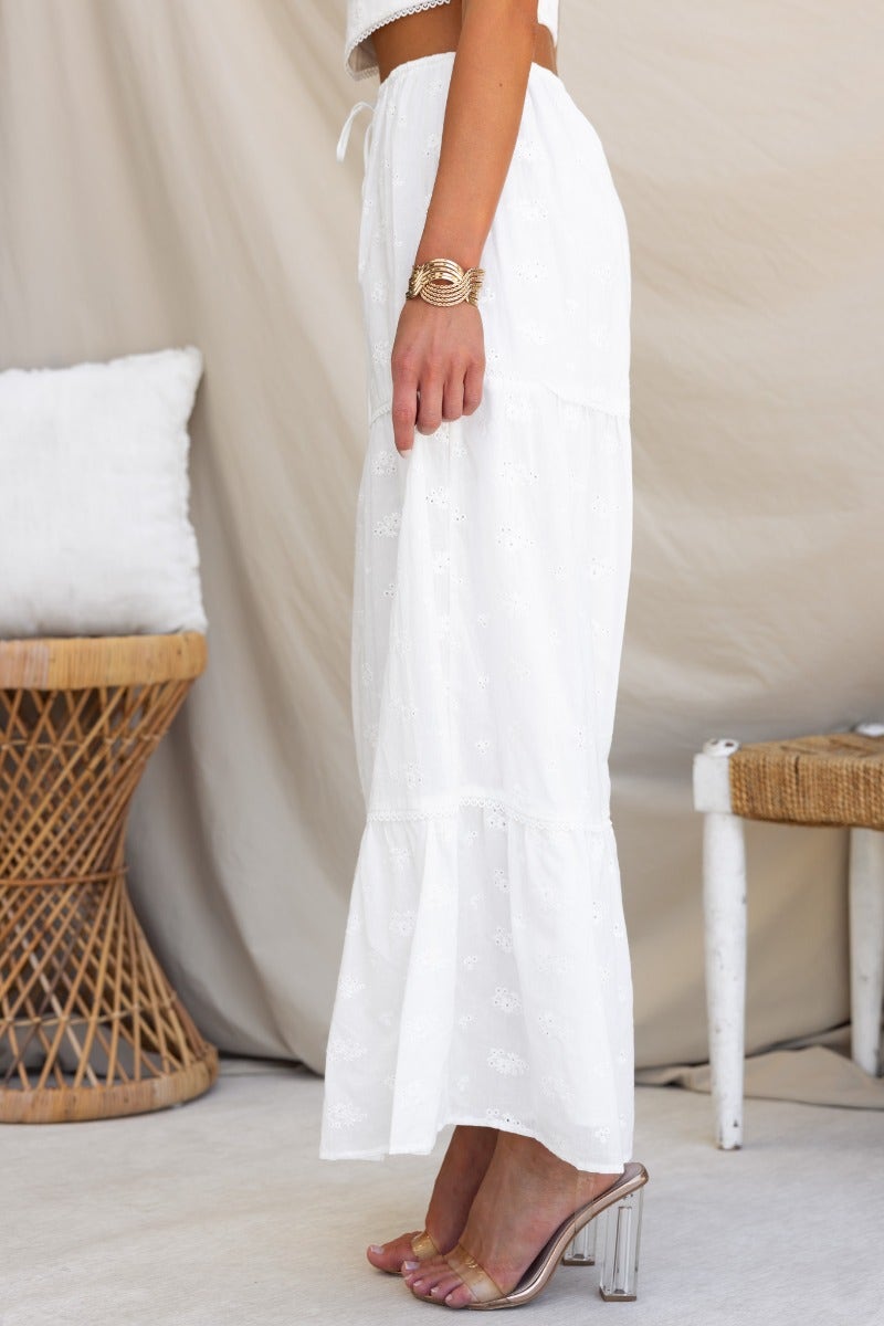 Model wearing a white Anglaise material long maxi skirt with elastic waistband and drawstring, styled for summer.