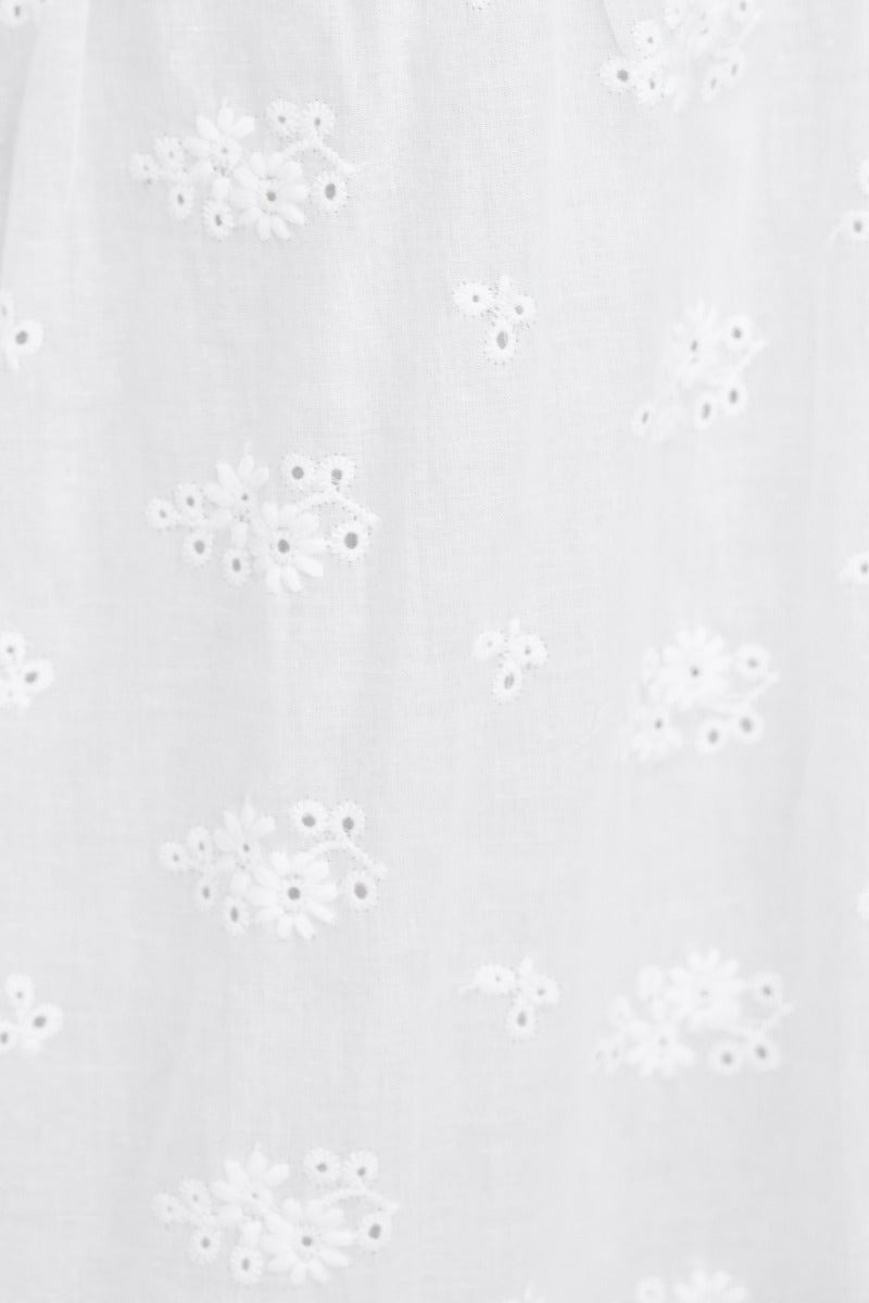 Close-up of delicate white Anglaise fabric with embroidered floral details, perfect for a long live maxi skirt.