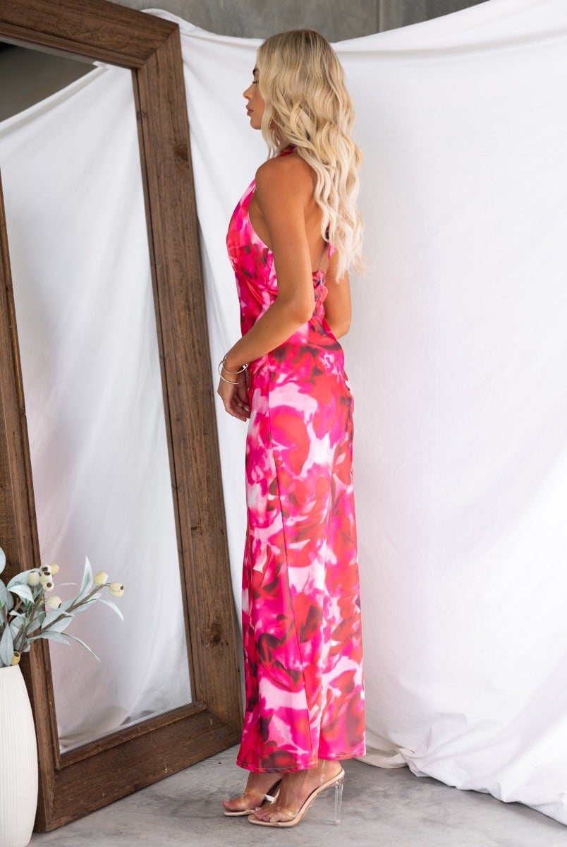 Model wearing Look Within Maxi Dress, featuring a vibrant floral print and adjustable halter neckline, in front of a mirror.