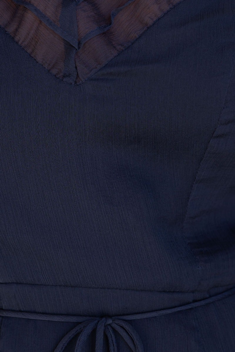 Close-up of the navy chiffon Encore Dress featuring a high neckline and elegant fabric tie detail.