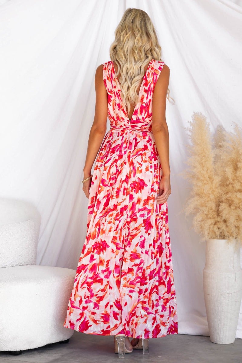 Back view of Suri Maxi Dress with colorful print, deep v-neckline, and high split, worn by a model.