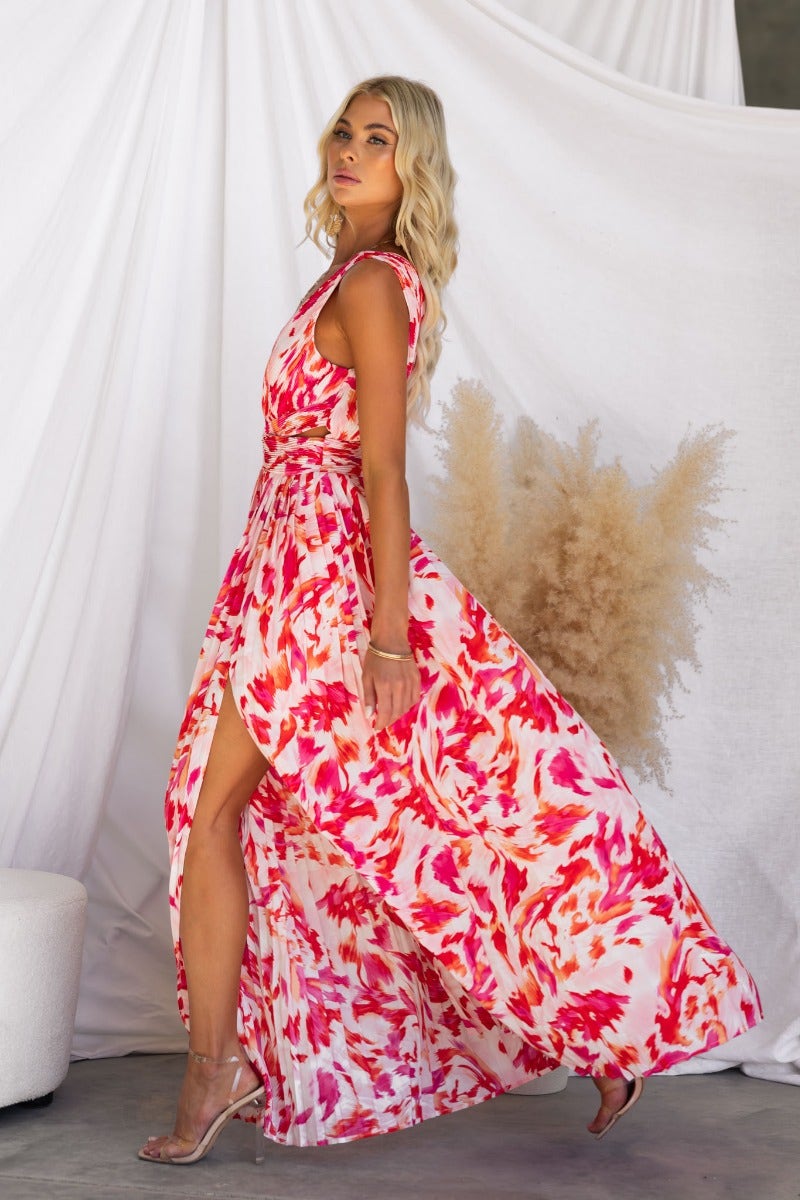 Model wearing the Suri Maxi Dress with a deep v-neckline and high split, featuring vibrant pink and orange floral design.