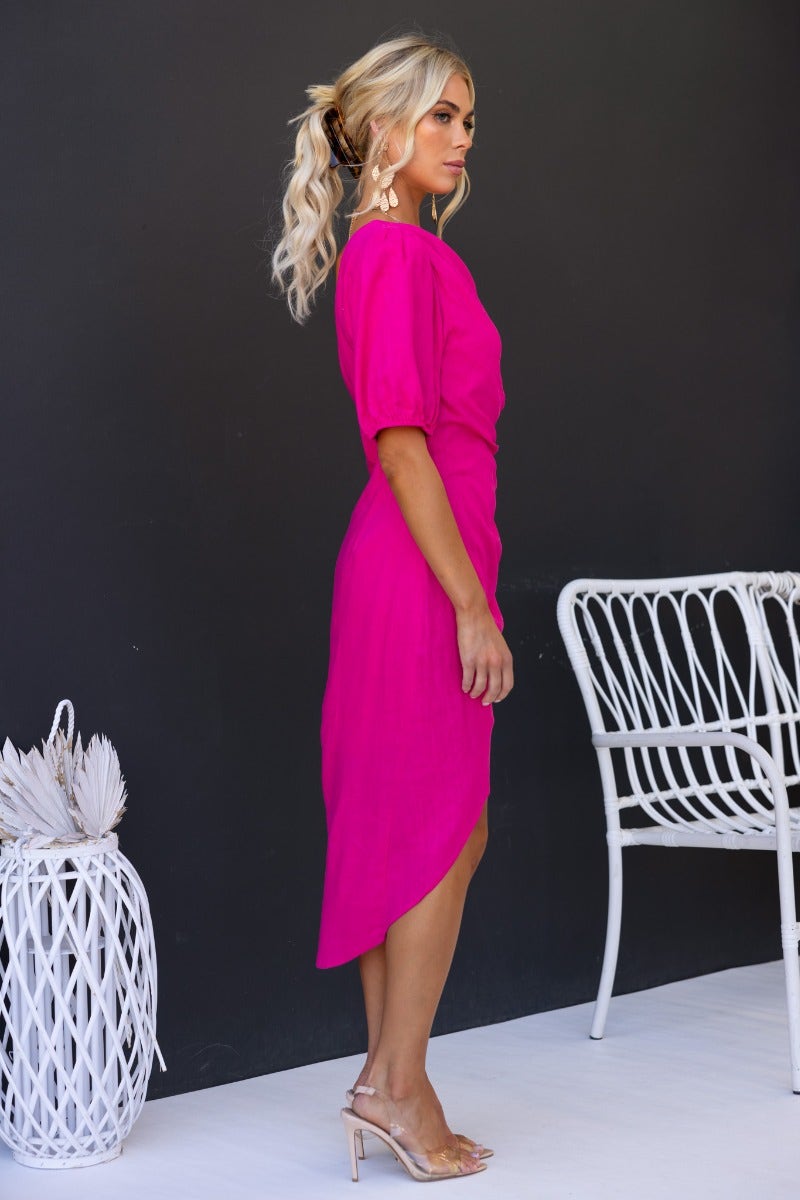 Side view of a model in a hot pink Last Kiss Midi Dress with one-shoulder neckline and asymmetric hem.