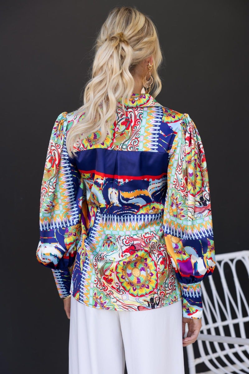Colorful Indianna Shirt with navy print and puff sleeves, viewed from the back, styled with white trousers.