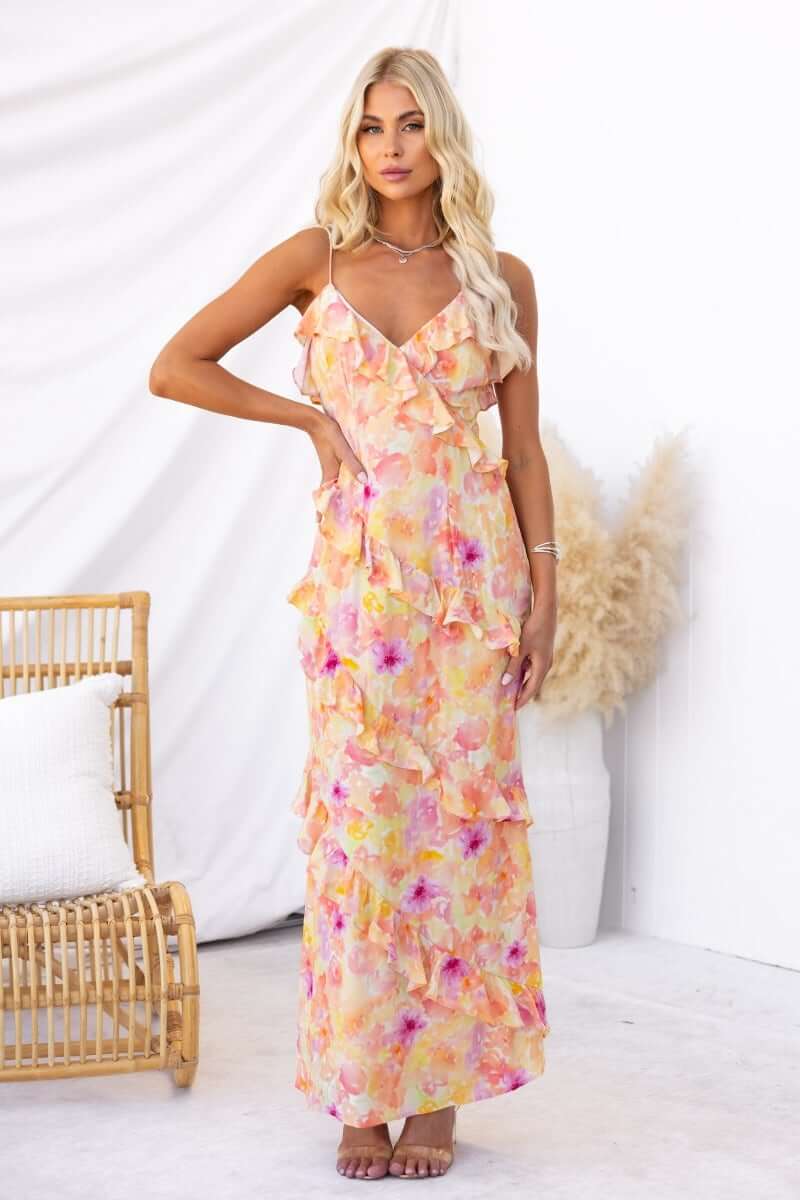 Floral print Aquarius Maxi Dress with adjustable straps and ruffle detailing, styled in a sunny setting.