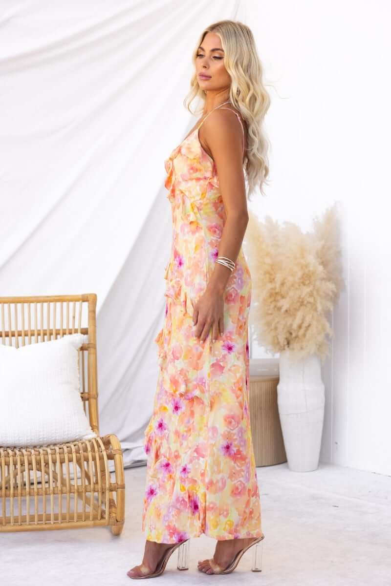 Model wears an Aquarius Maxi Dress with floral print and adjustable straps, set against a stylish backdrop.