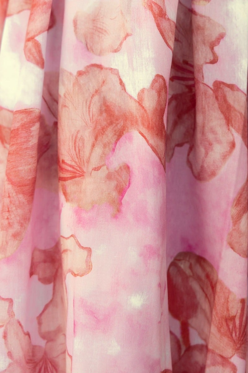 Close-up of a soft pink fabric with floral watercolor patterns, perfect for a cheerful dress design.