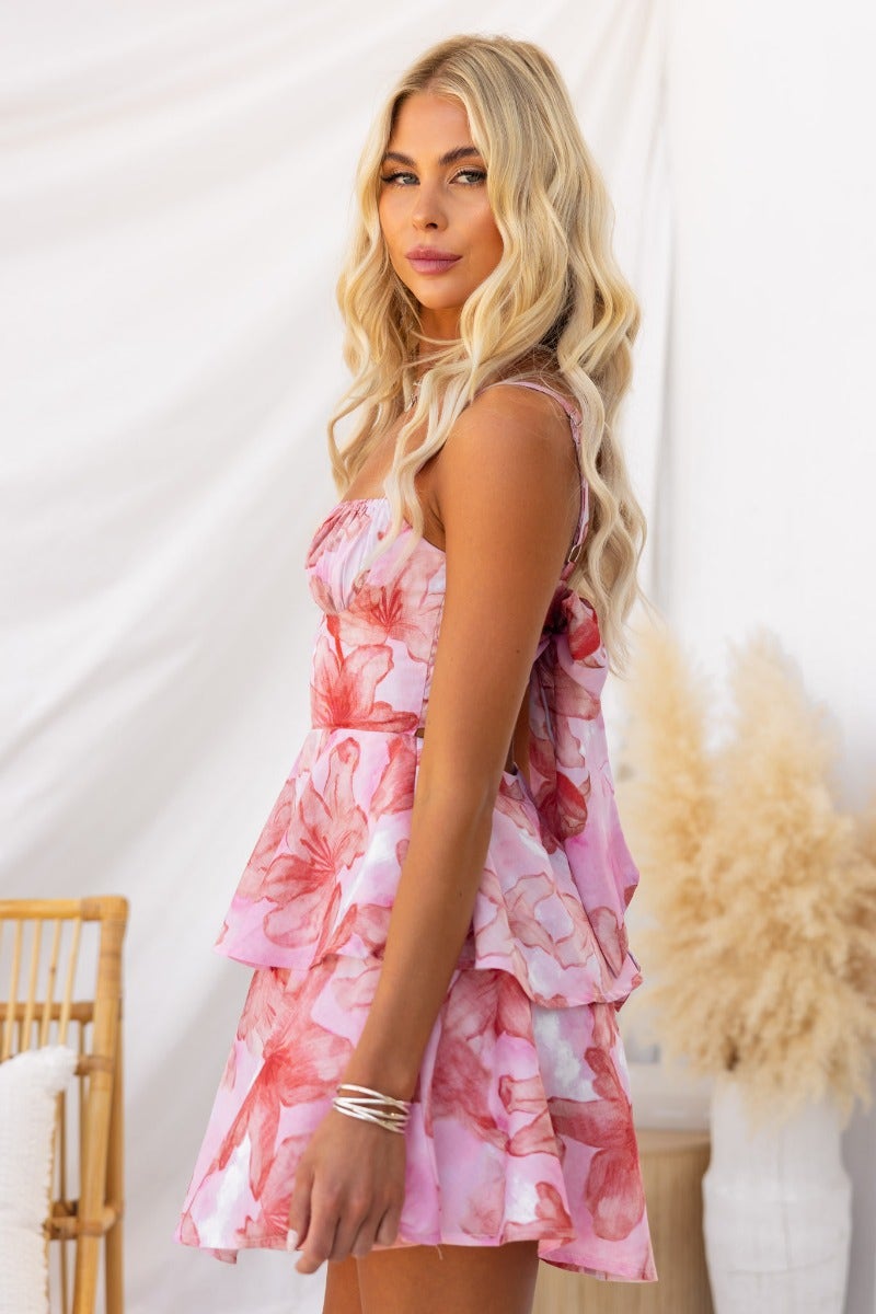 Woman wearing the Dear Diary floral print dress with adjustable straps and a tiered ruffle design.