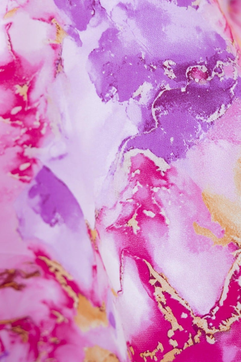 Close-up of vibrant pink and purple floral satin fabric with metallic gold accents, perfect for an elegant maxi dress.