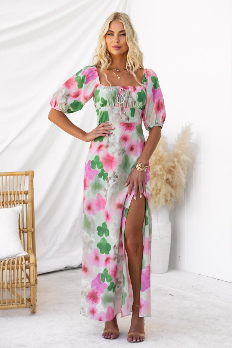 Eyre Maxi Dress featuring floral print, elastic sleeves, tie bust detail, and a front split, modeled by a woman.