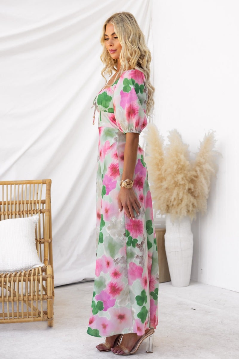 Model wearing a floral print Eyre Maxi Dress with elastic sleeves and tie detail, styled in a bright and airy setting.
