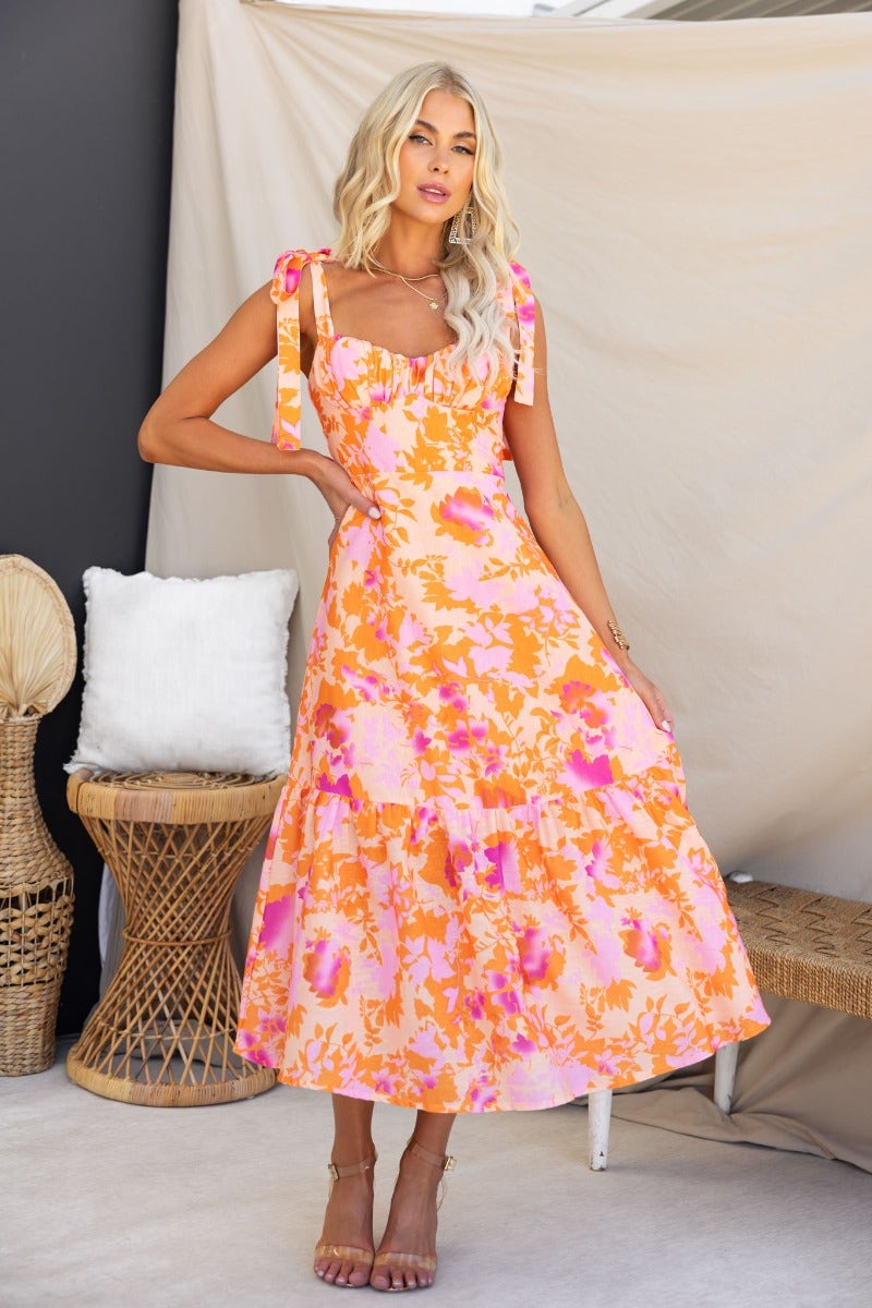 Floral print Gratified midi dress with adjustable tie straps and padded bust, styled with a natural background.