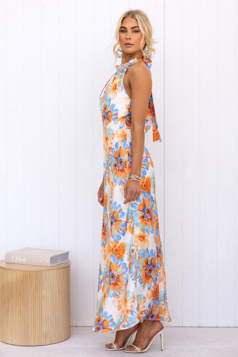 Model wearing a floral print satin maxi dress with a high tie neckline, showcasing vibrant blue and orange flowers.