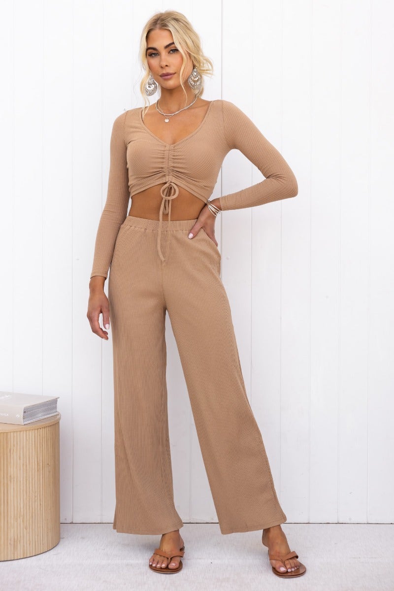 Model wearing Smitten Pants, ribbed knit with elastic waistband and wide legs, styled with a matching long-sleeve top.