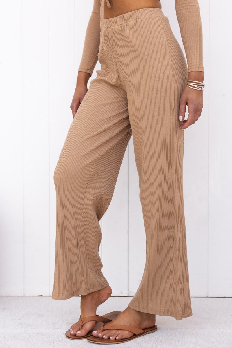 Woman wearing Smitten Pants, ribbed knit beige wide-leg pants with an elastic waistband and no lining.