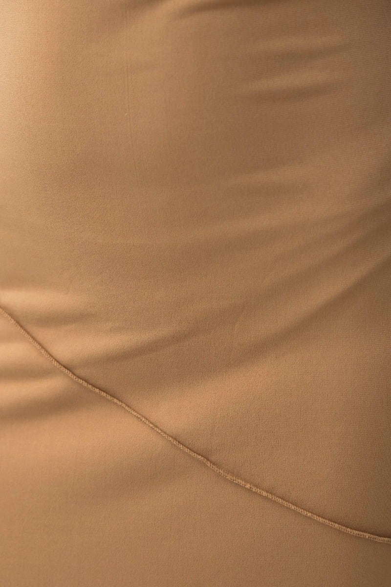 Close-up of the smooth fabric texture of the Kaitey Maxi Dress in tan, showcasing its stretch material and tailored design.