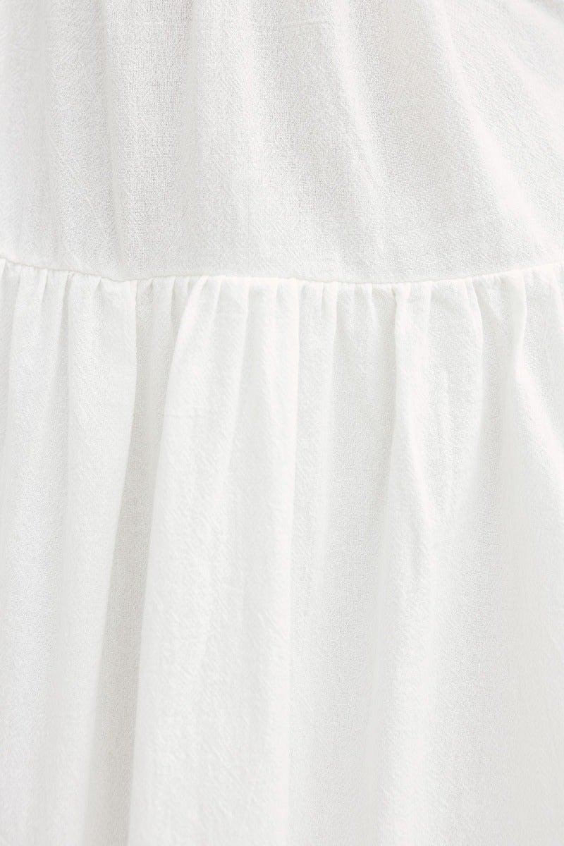 Close-up of Ramilah Midi Dress fabric, showcasing soft white cotton with gathered detail, perfect for summer wear.