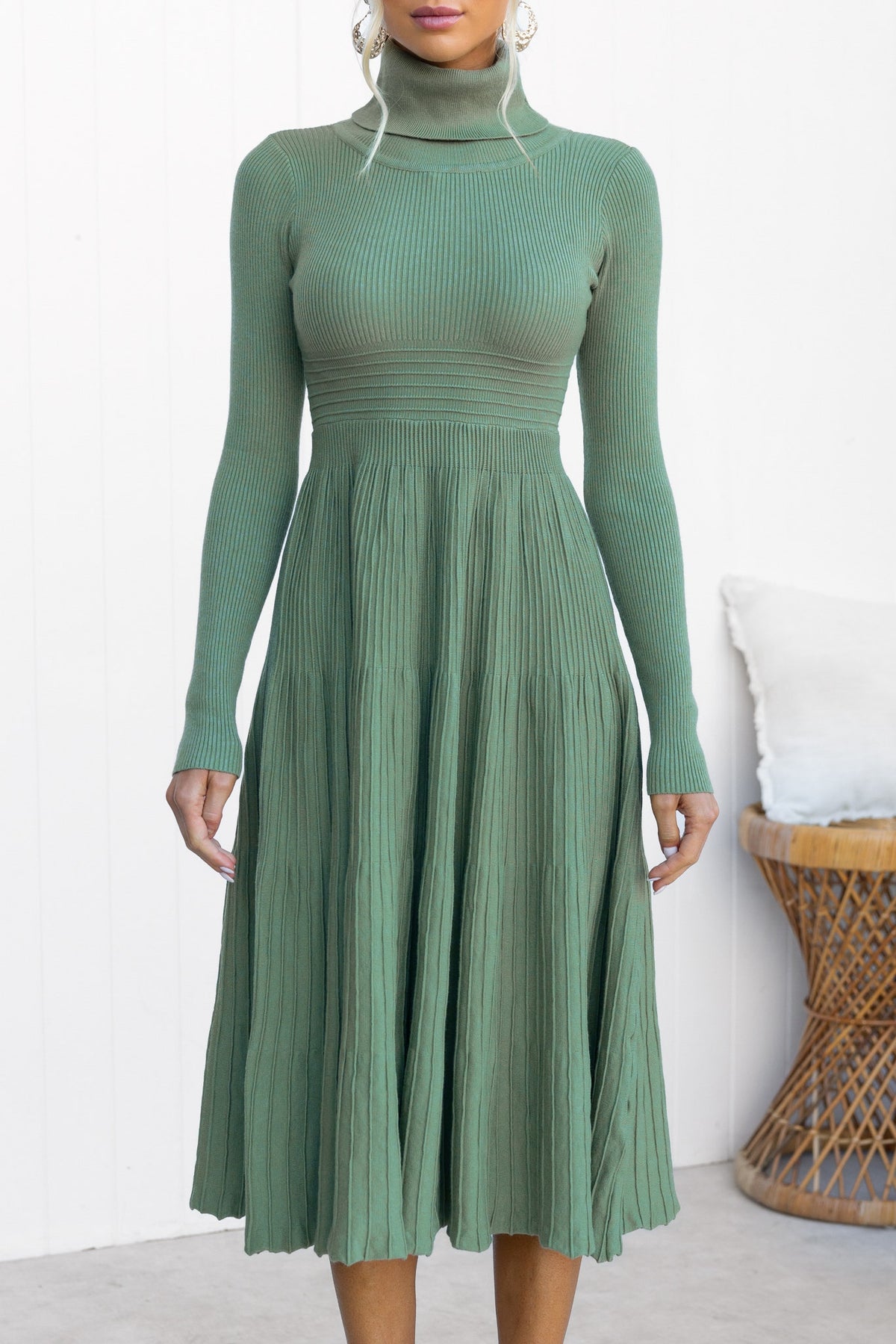 Green midi dress with turtle neckline and ribbed knit design, showcasing a flowy pleated skirt.