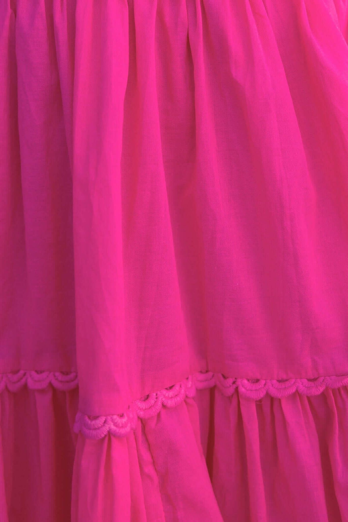 Close-up of the Verlaine Dress in vibrant pink, featuring textured fabric and decorative stitching on the tiers.