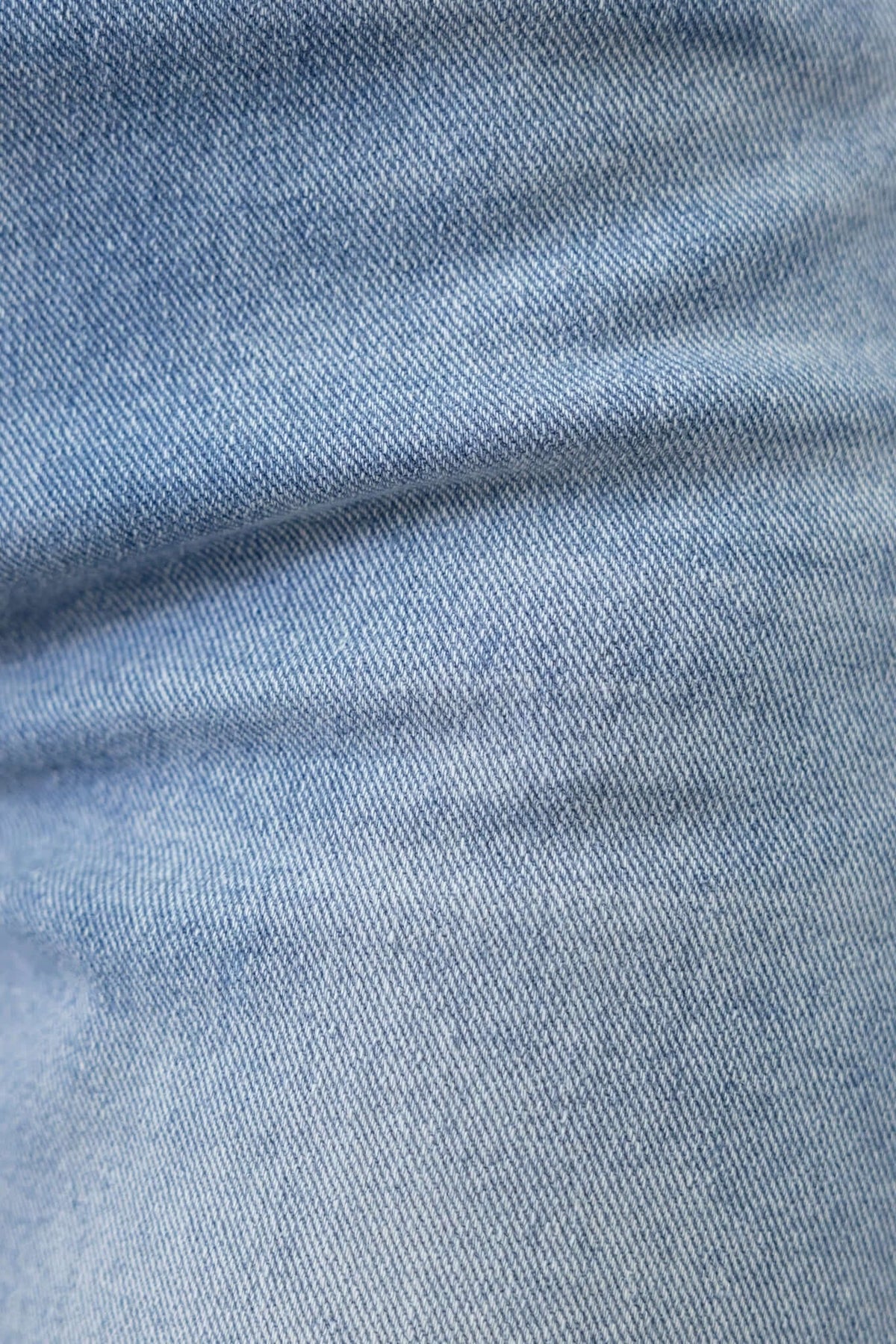 Close-up of light wash denim fabric showing texture and stretch in Tekin jeans.
