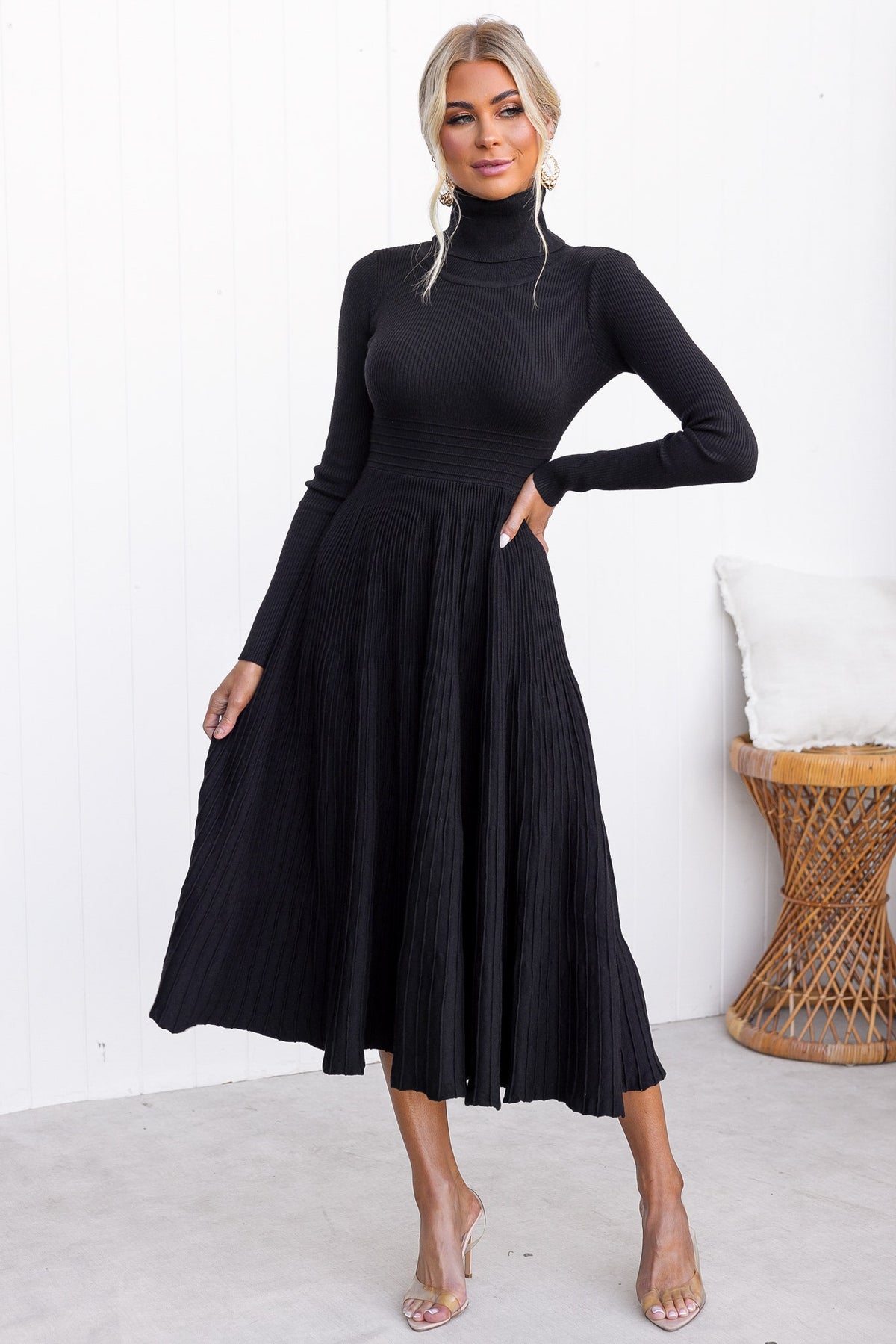 Black midi dress with a turtle neckline in ribbed knit, featuring pleated skirt and stretchy fabric, perfect for stylish occasions.