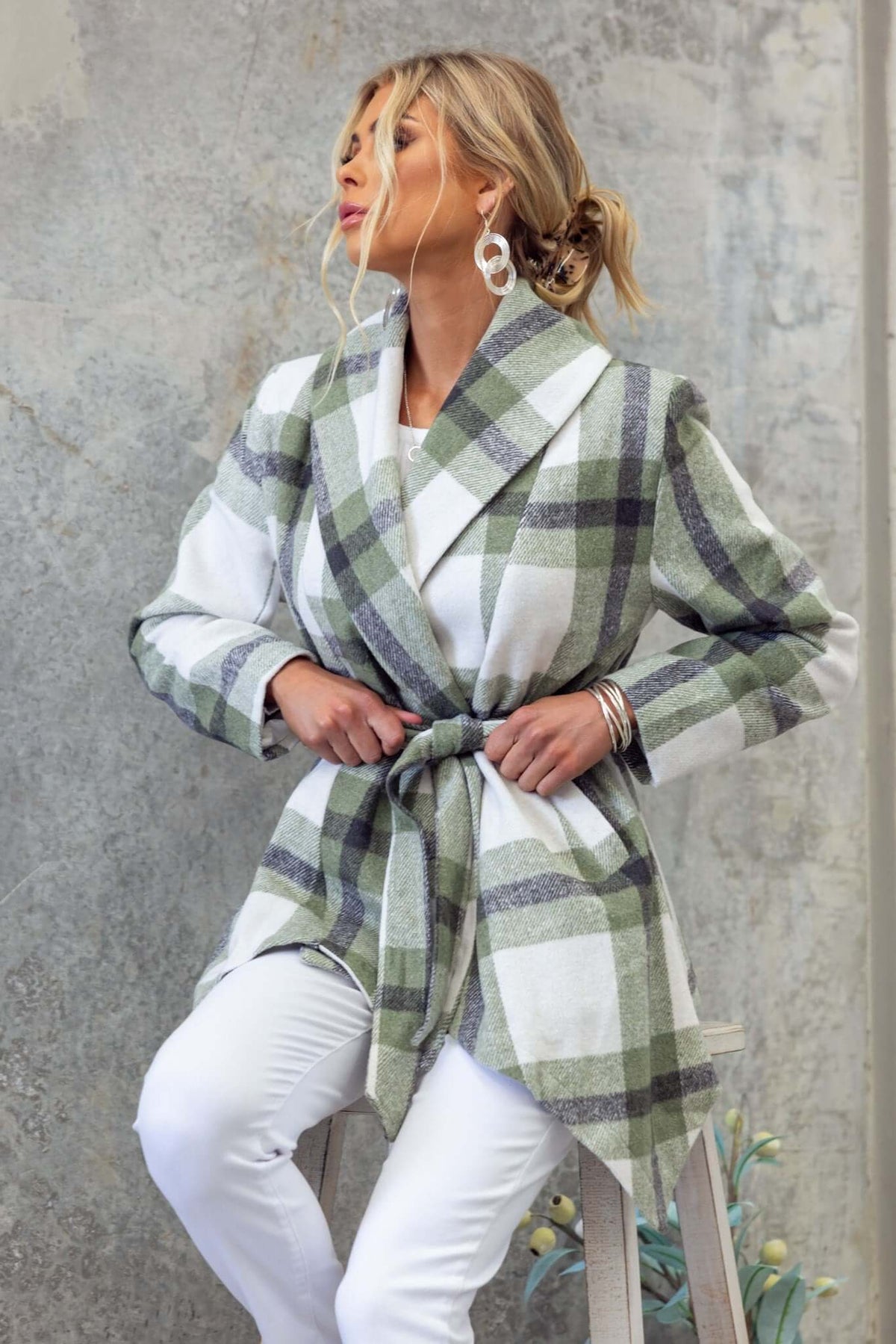 Stylish Phillips coat in green and white plaid with a removable tie, worn by a model against a textured background.