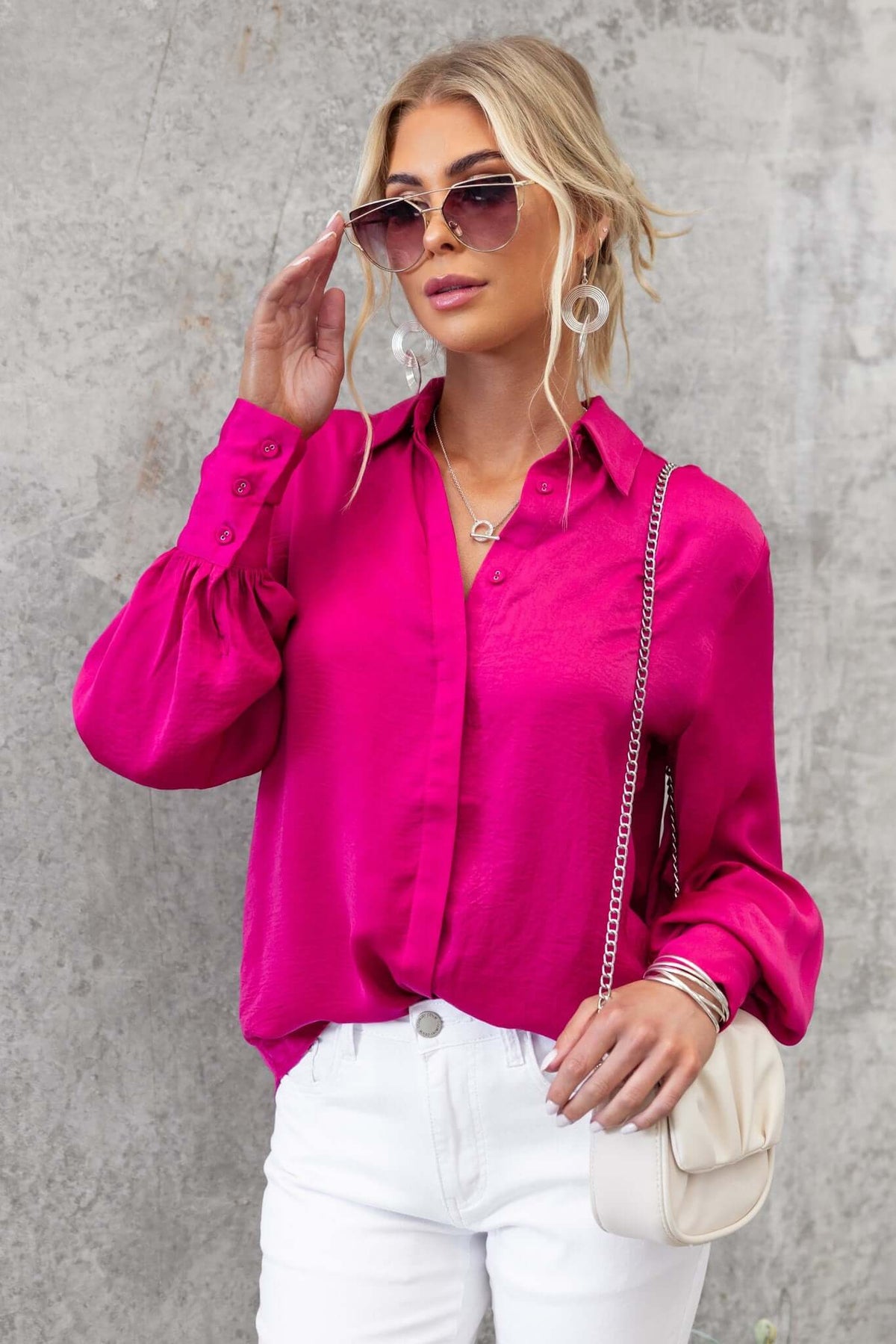 Model wearing a vibrant pink Ravia Shirt with button-up front, styled with sunglasses and white jeans.