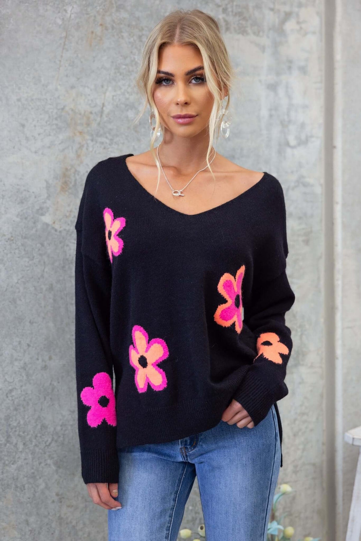 Model wearing a black Kamen Jumper with colorful flower patches, featuring a relaxed fit and V-neckline.