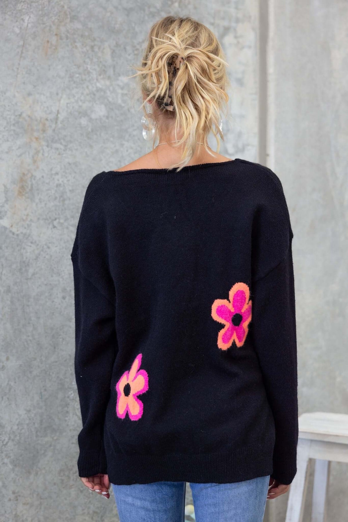 Back view of Kamen Jumper, black knit sweater with colorful flower designs, featuring a relaxed fit and V-neckline.
