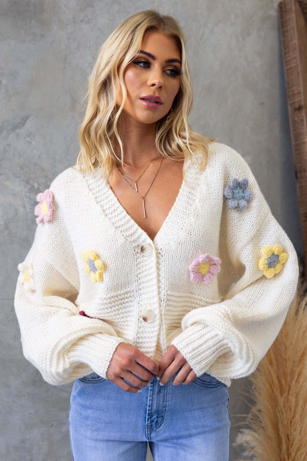 Model wearing Love Bug Cardigan, a cozy knit cardigan with colorful flower appliques and a V-neckline.