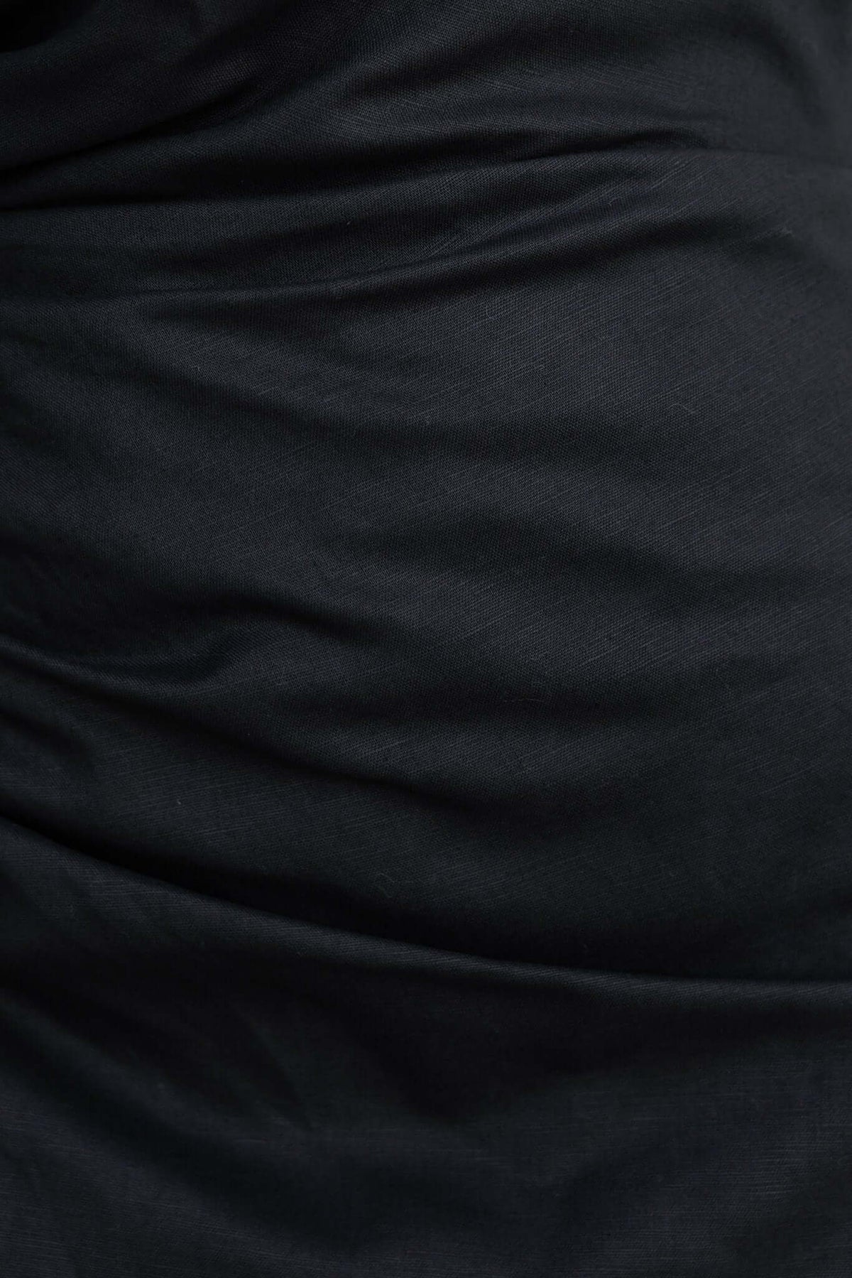 Close-up of fabric texture of black Delgado Maxi Dress, showcasing linen-like feel with subtle draping.