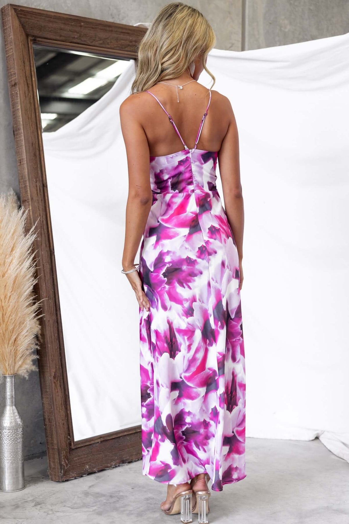 Back view of a woman in a floral Kasian maxi dress with adjustable straps and a lined design.