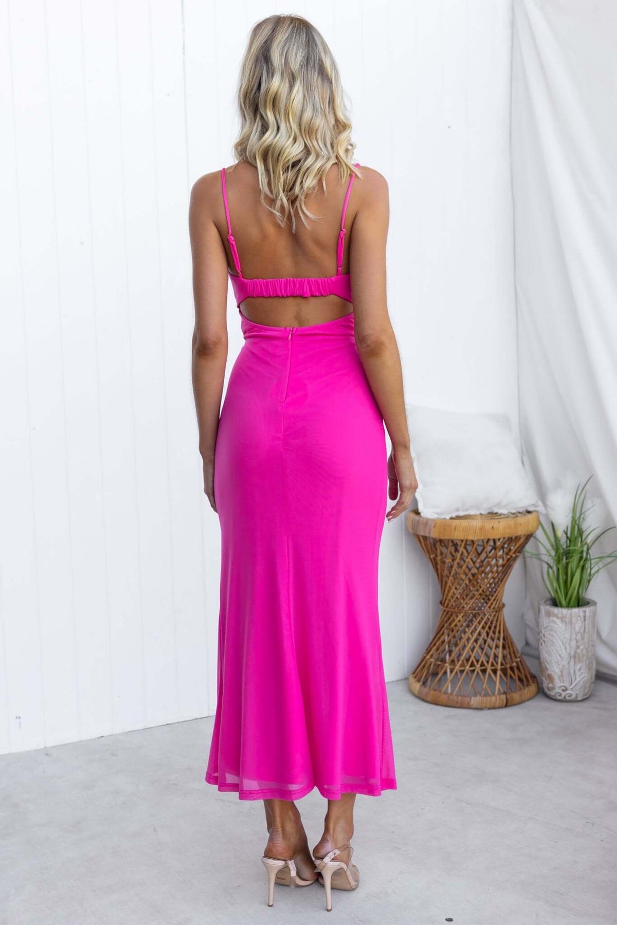 Back view of a woman wearing a pink Tropicale Maxi Dress with adjustable straps and a tie waist.
