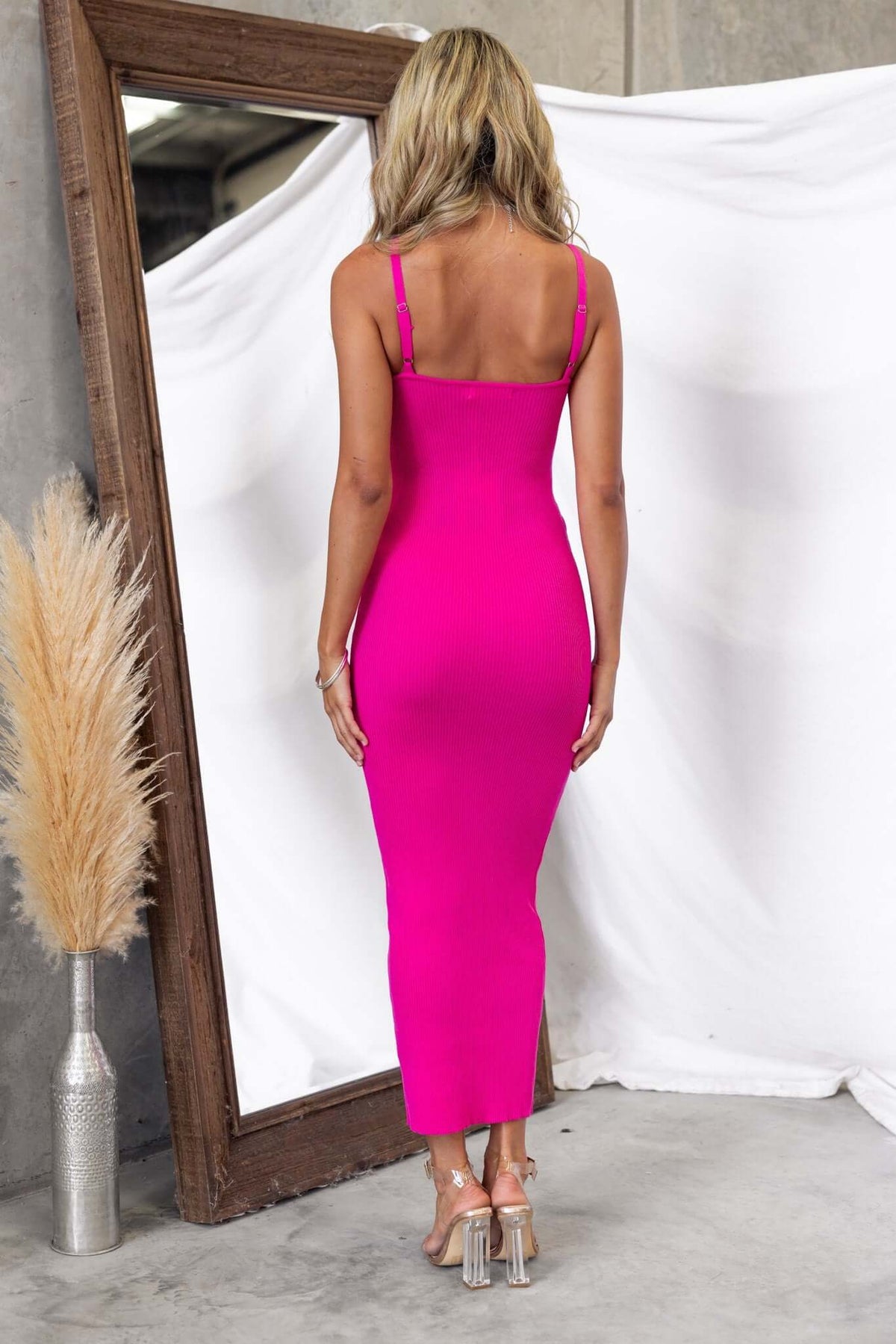 Back view of a woman wearing a vibrant pink Viviana maxi dress in a stylish setting.