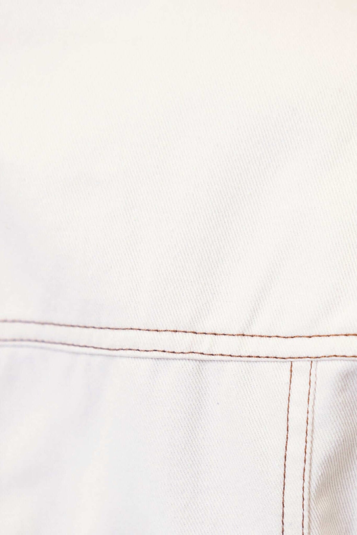 Close-up of the fabric texture and stitching of the Lisa Denim Dress in cream color.