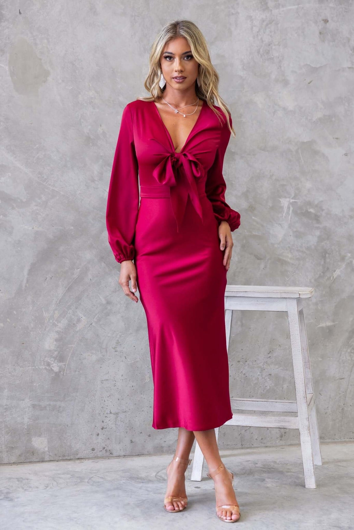 Cremona Midi Dress in deep red featuring a tie at the bust and elastic sleeves, styled elegantly with a satin finish.