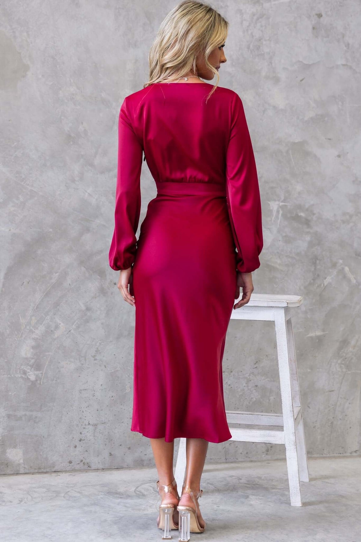 Back view of a woman in a deep red Cremona Midi Dress with long sleeves and a fitted silhouette.