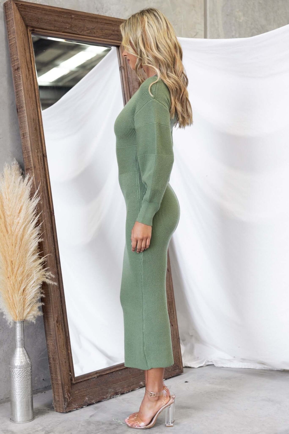 Model wearing Farina Maxi Dress in green, showcasing side profile and V-neckline in ribbed knit material.