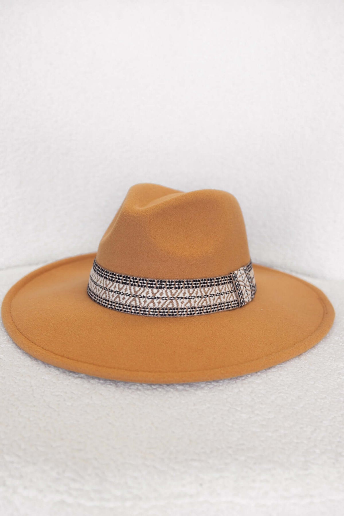 Stylish Kansas hat with a wide brim and patterned ribbon trim, featuring a soft, mustard color.