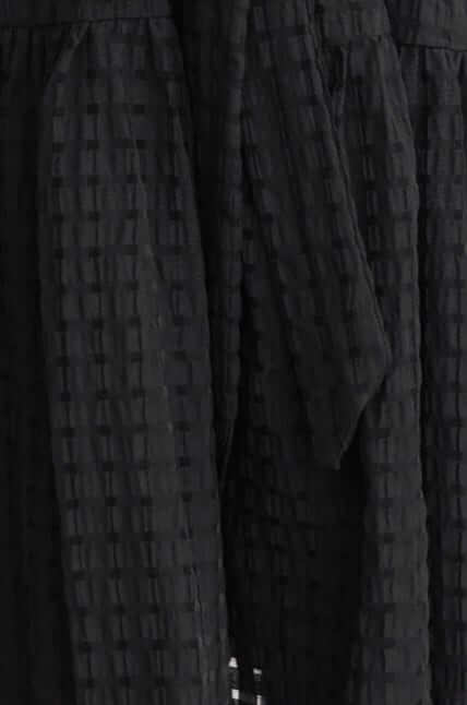 Close-up of the Cottee Dress showing the textured black fabric and removable tie detail.