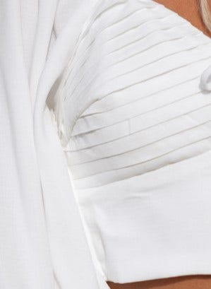 Close-up of Flaria Top featuring sweetheart neckline, tie detail, and elastic sleeve fittings in elegant white fabric.