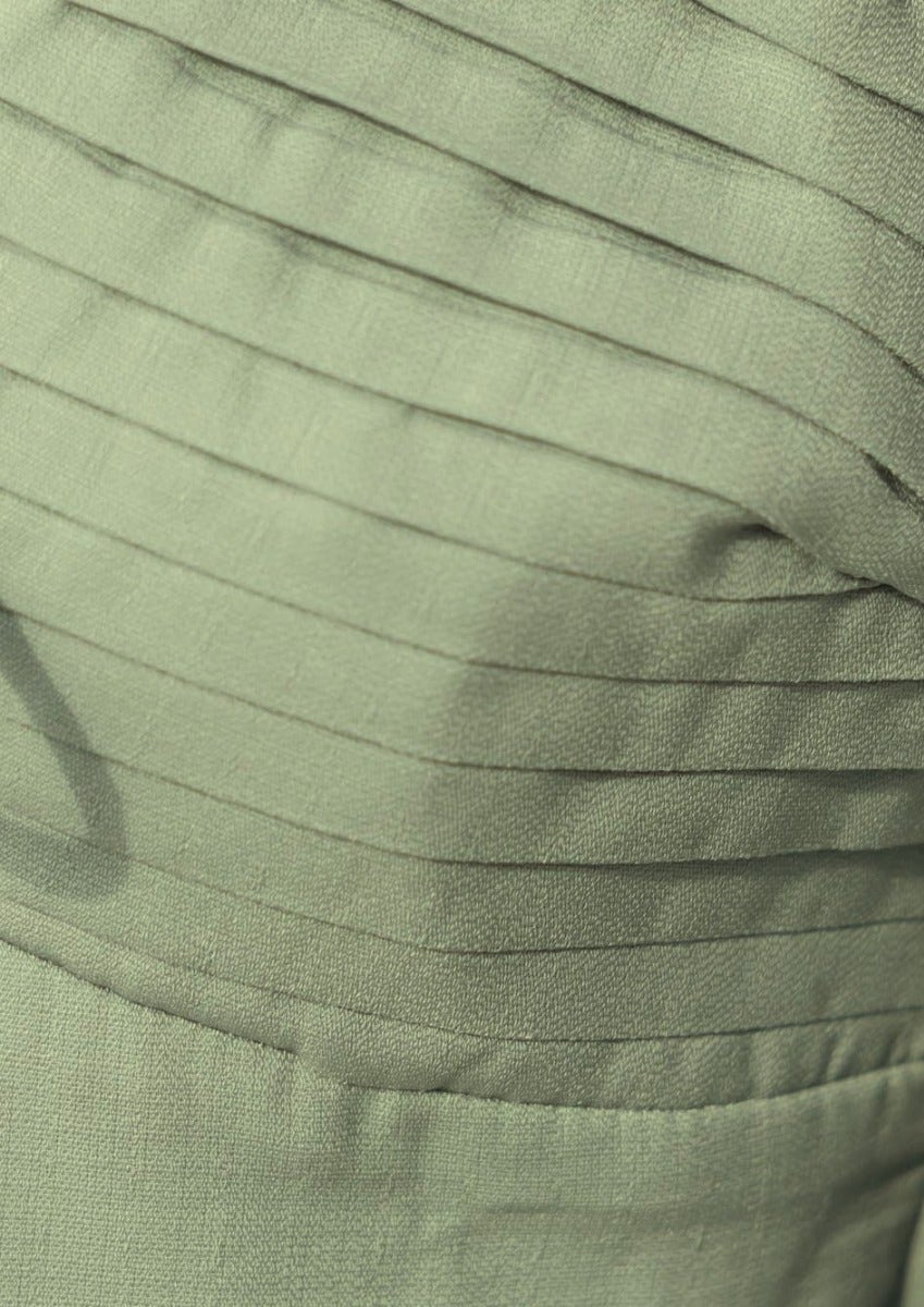 Close-up of Flaria Top's textured green fabric featuring delicate pleats and soft sheen for elegant styling.