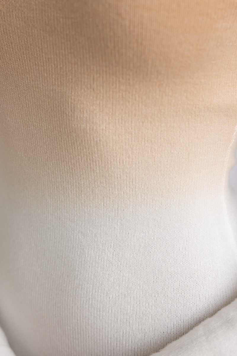 Close-up of ribbed knit fabric in an ombre beige to white gradient, showcasing texture and softness.