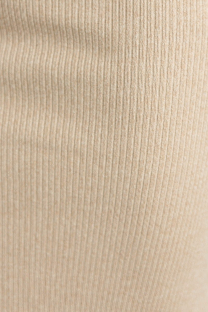 Close-up of ribbed fabric texture in a beige color, highlighting the soft stretch material of the Leslie Midi Dress.