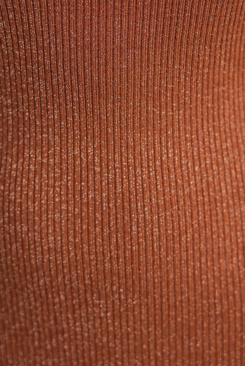 Close-up of ribbed knit fabric in a warm rust color, featuring subtle glitter for a stylish look.