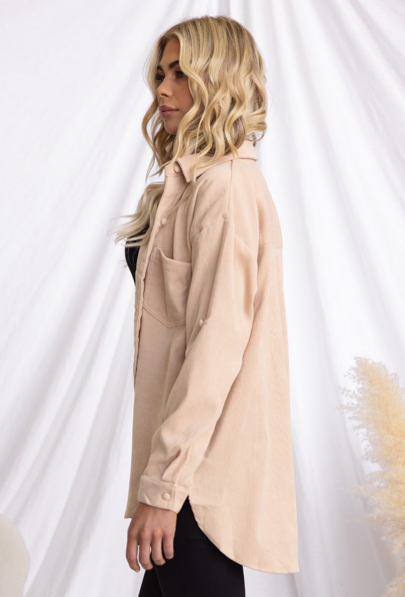 Model wearing a stone corduroy shirt with a button-up front and a pocket, showcasing a relaxed fit.