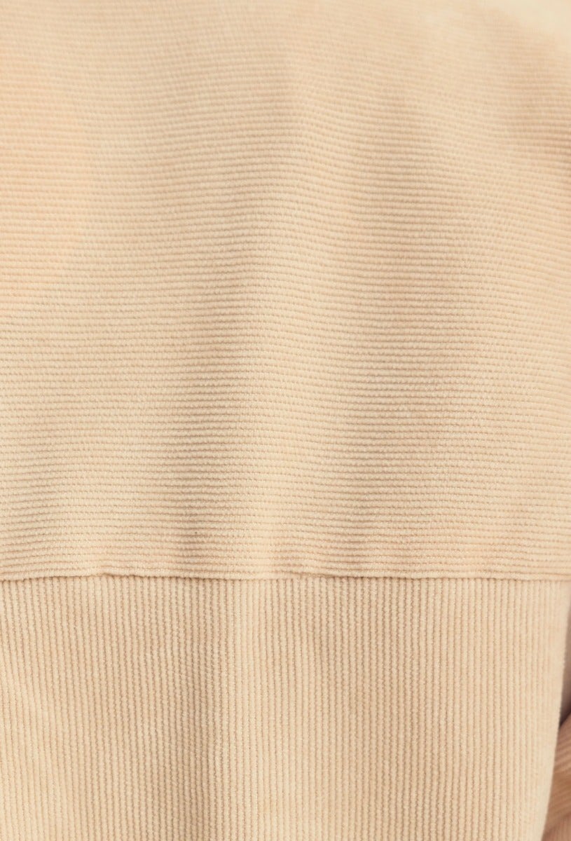Close-up of light tan corduroy fabric showcasing texture, ideal for a stylish and comfortable button-up shirt.