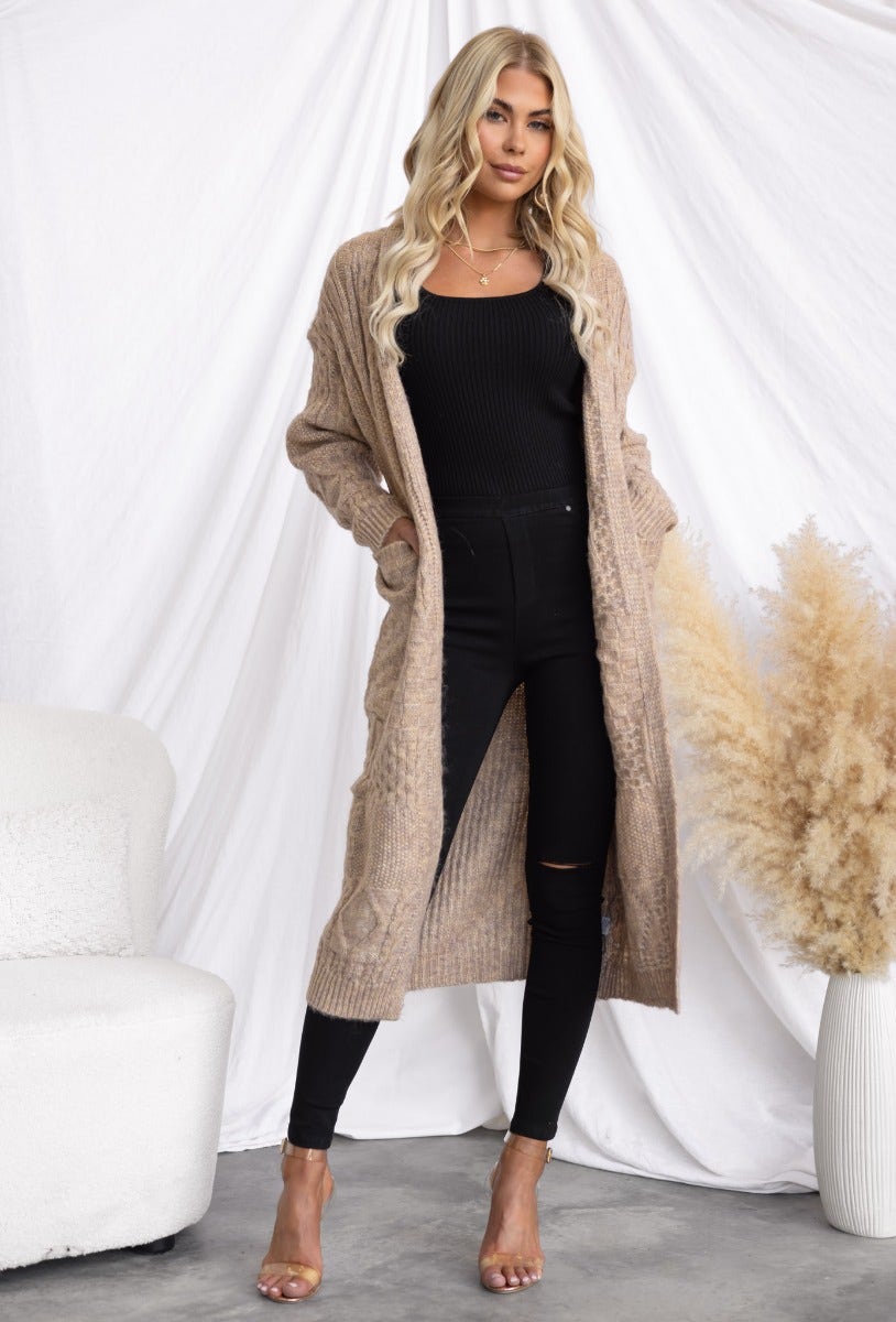 Stylish Emerson cardigan in cable knit, worn by a model with long hair, featuring a longline fit and pockets.