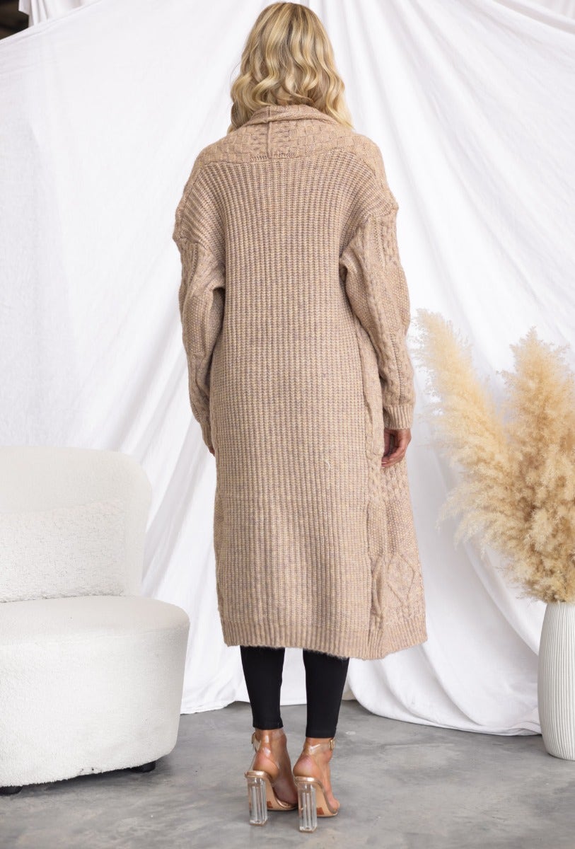 Back view of a longline cable knit Emerson cardigan in beige, styled with black leggings, perfect for cozy casual wear.